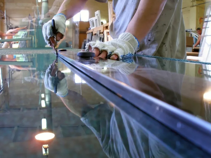 Atelier de découpe du verre avec artisan traçant une plaque — Clarté Vitrerie